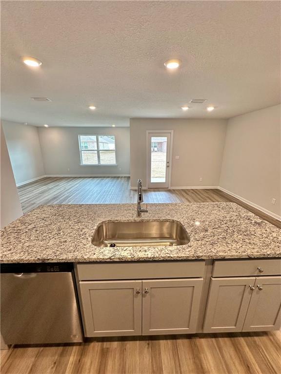 kitchen featuring sink, light hardwood / wood-style flooring, light stone countertops, and dishwasher