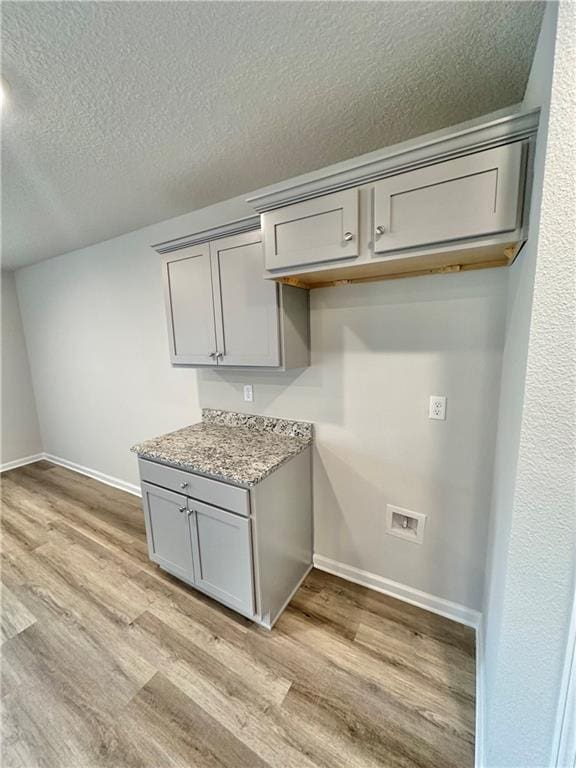 kitchen featuring light stone counters, light hardwood / wood-style flooring, a textured ceiling, and gray cabinets