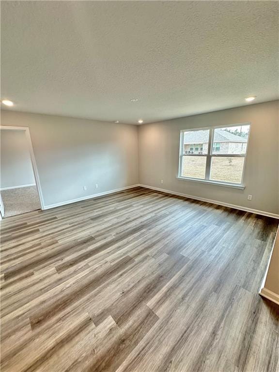 empty room featuring a textured ceiling and light hardwood / wood-style flooring