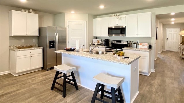 kitchen featuring stainless steel appliances, an island with sink, a breakfast bar area, and white cabinets