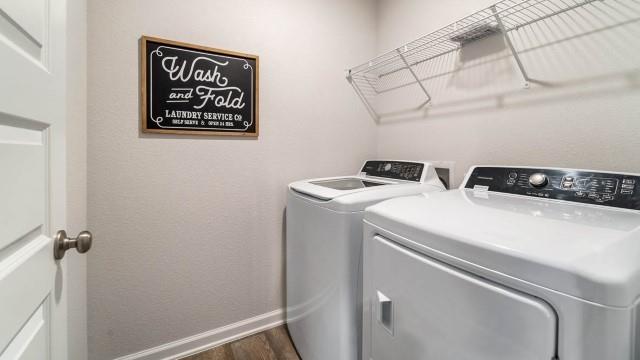 clothes washing area with washing machine and dryer and dark wood-type flooring