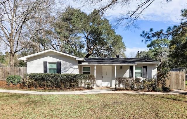 ranch-style home with a front lawn and fence