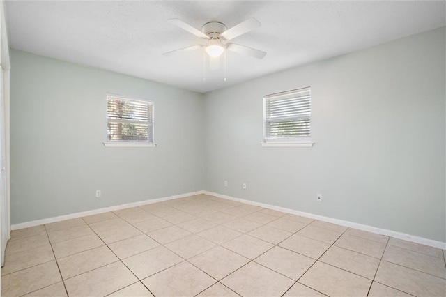 spare room featuring baseboards, a ceiling fan, and a wealth of natural light