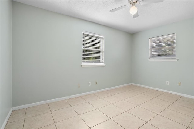 spare room with baseboards, a ceiling fan, and a healthy amount of sunlight