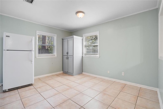 spare room with ornamental molding, a healthy amount of sunlight, baseboards, and light tile patterned floors