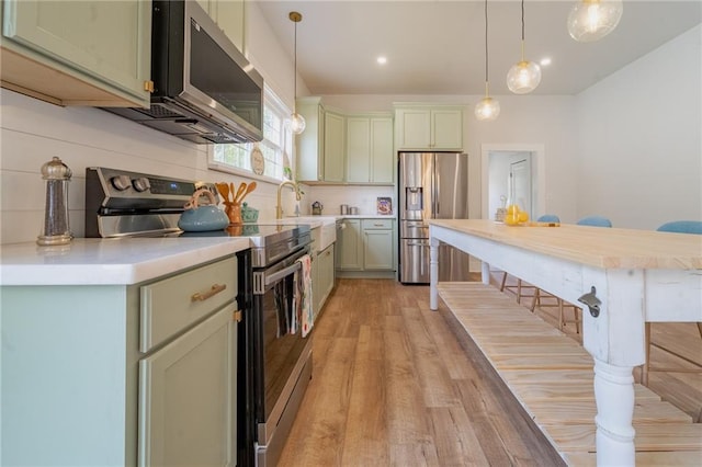 kitchen featuring tasteful backsplash, appliances with stainless steel finishes, pendant lighting, and light countertops