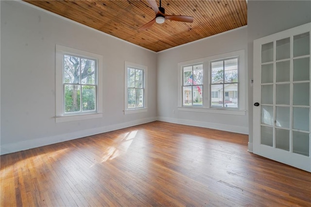 empty room with a ceiling fan, baseboards, ornamental molding, wood-type flooring, and wooden ceiling