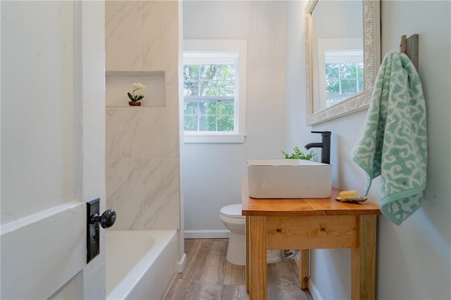 full bath with wood finished floors, toilet, a bath, and a wealth of natural light