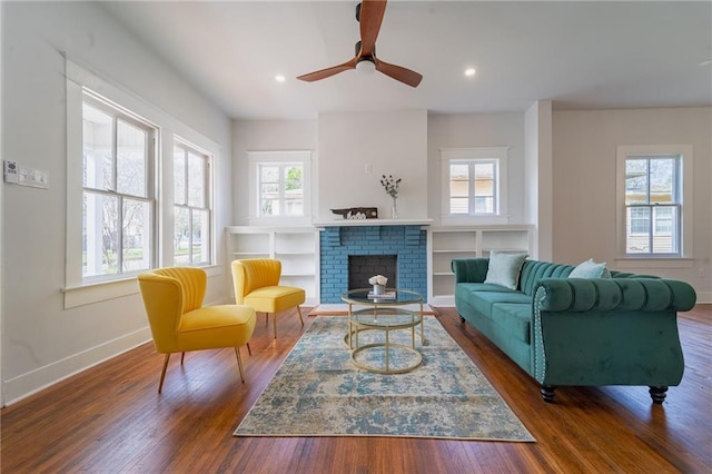 living area featuring hardwood / wood-style flooring, a brick fireplace, recessed lighting, and baseboards