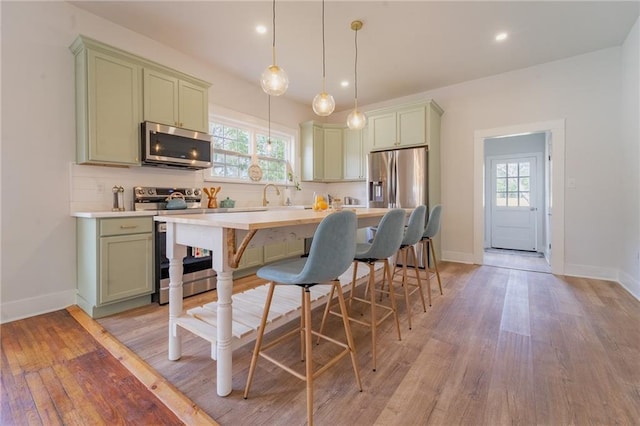 kitchen with backsplash, green cabinets, stainless steel appliances, and light countertops