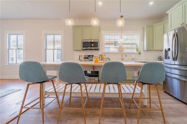 kitchen with decorative backsplash, plenty of natural light, green cabinetry, and stainless steel appliances