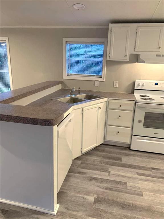 kitchen with white appliances, dark countertops, a sink, and white cabinetry