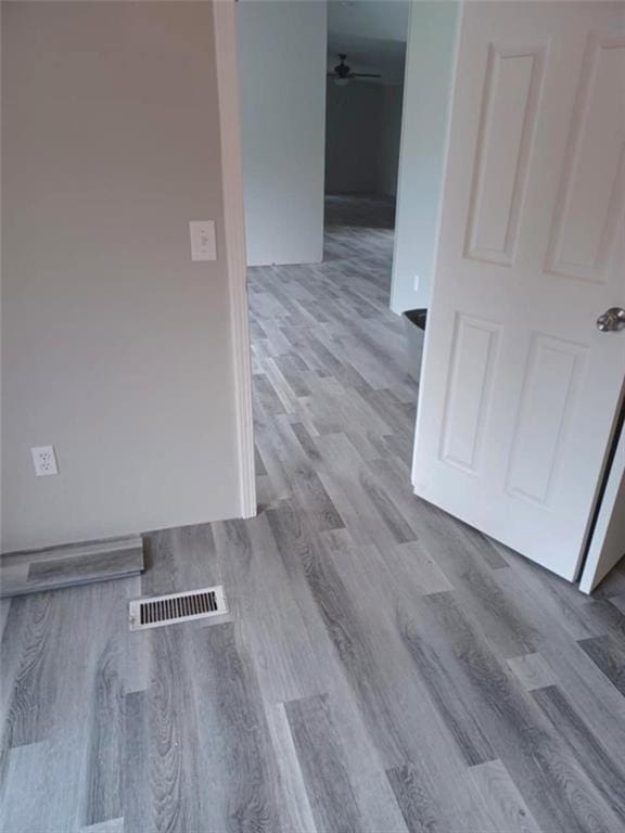 interior space with a ceiling fan, visible vents, and wood finished floors