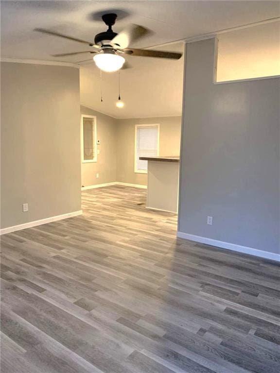 empty room featuring lofted ceiling, ceiling fan, baseboards, and wood finished floors