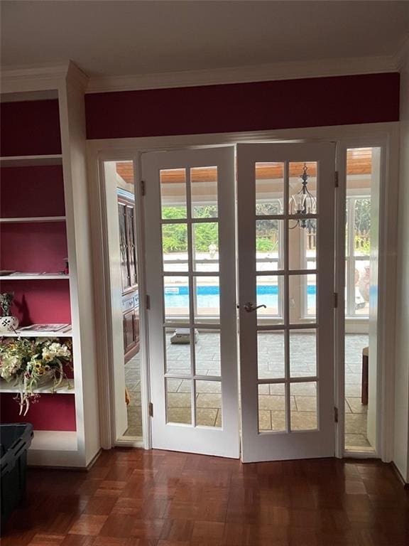 doorway featuring a notable chandelier, dark parquet floors, crown molding, and french doors