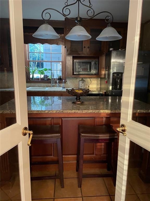 kitchen featuring stone counters, sink, tasteful backsplash, tile patterned floors, and appliances with stainless steel finishes