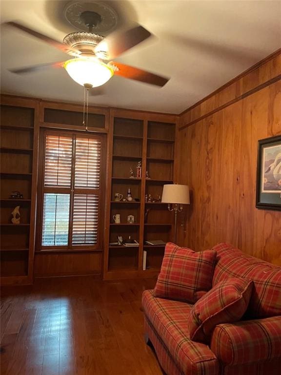 living area featuring ceiling fan, wood walls, dark hardwood / wood-style flooring, and built in features