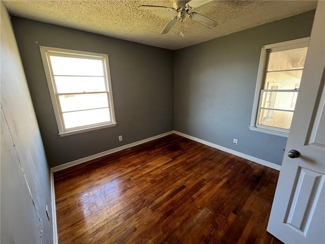 spare room with a textured ceiling, ceiling fan, and dark hardwood / wood-style floors