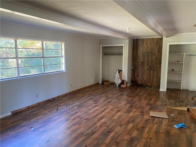 unfurnished bedroom featuring multiple closets, beamed ceiling, dark hardwood / wood-style floors, and a textured ceiling