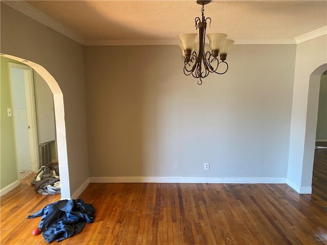 spare room with dark wood-type flooring, ornamental molding, a textured ceiling, and a notable chandelier