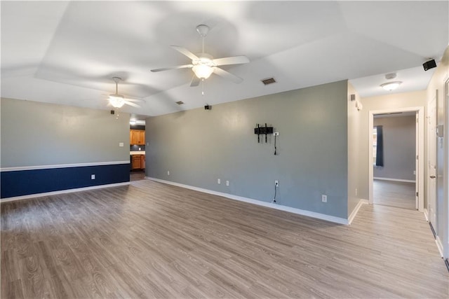 spare room with ceiling fan, vaulted ceiling, and light hardwood / wood-style flooring