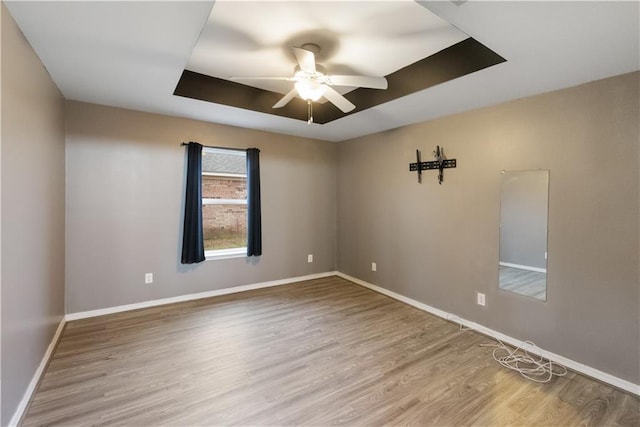 spare room featuring a tray ceiling, hardwood / wood-style flooring, and ceiling fan