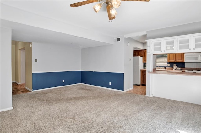 unfurnished living room featuring light colored carpet and ceiling fan