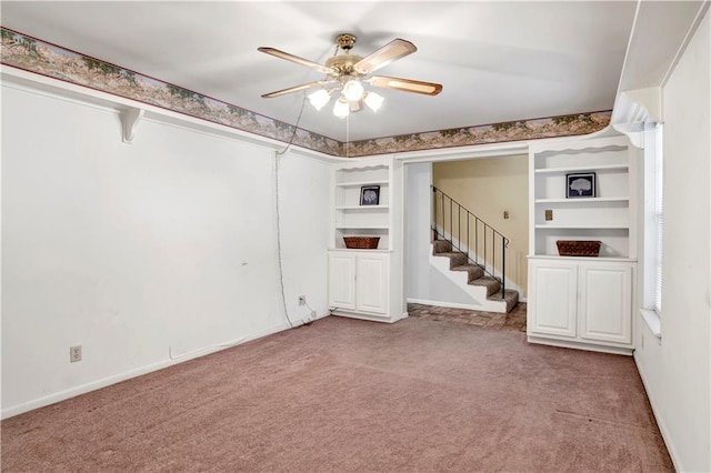 basement with light carpet, built in features, and ceiling fan