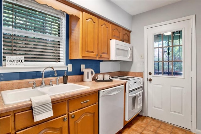 kitchen with sink, light tile patterned floors, and white appliances