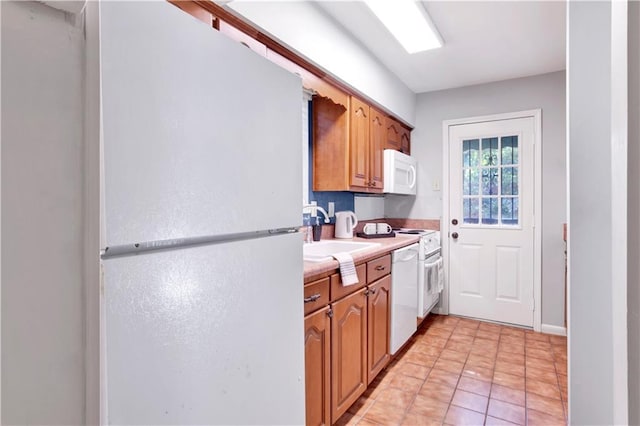 kitchen featuring light tile patterned flooring, white appliances, and sink