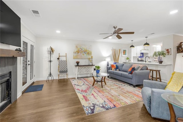 living room with crown molding, ceiling fan, sink, and hardwood / wood-style floors