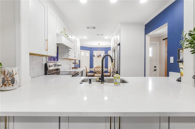 kitchen with sink, white cabinetry, ornamental molding, appliances with stainless steel finishes, and kitchen peninsula