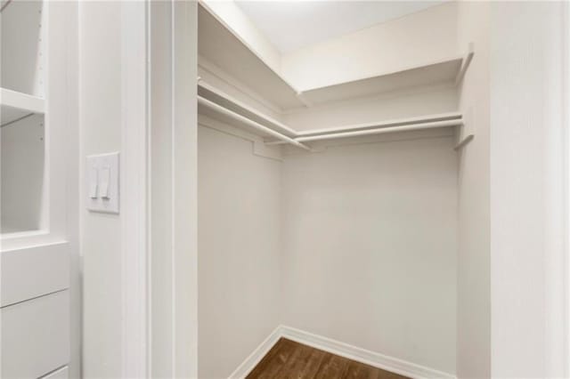 walk in closet with dark hardwood / wood-style flooring