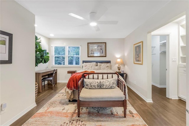 bedroom with ceiling fan, a walk in closet, and dark hardwood / wood-style floors