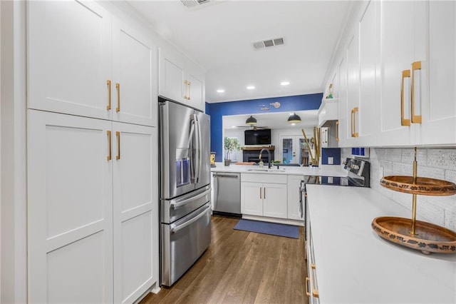 kitchen with stainless steel appliances, white cabinetry, wood-type flooring, and decorative backsplash