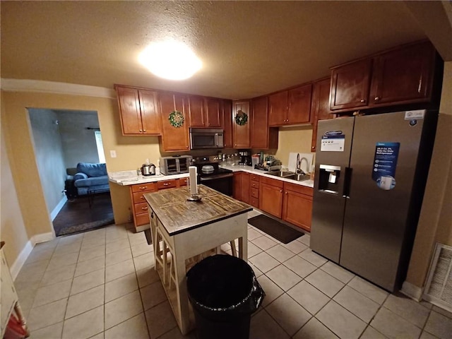 kitchen featuring a textured ceiling, sink, light tile patterned floors, and stainless steel appliances