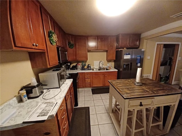 kitchen with light tile patterned floors, a textured ceiling, sink, and appliances with stainless steel finishes