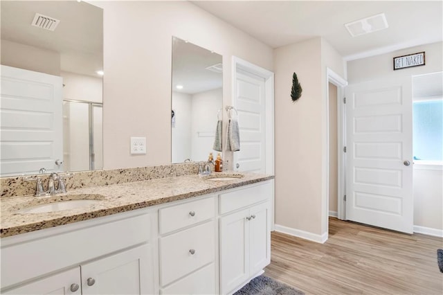 full bathroom with double vanity, wood finished floors, a sink, and visible vents