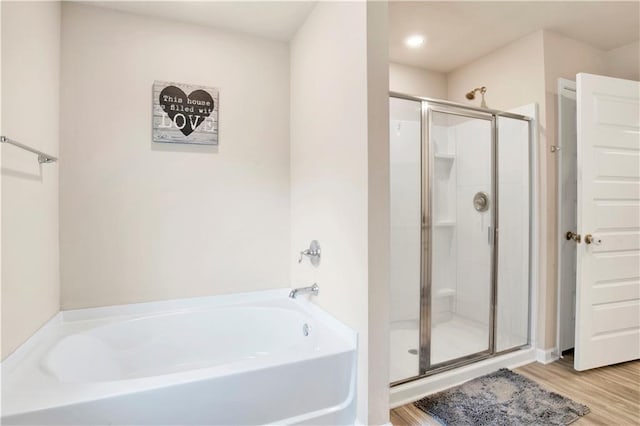 full bathroom featuring a garden tub, a shower stall, and wood finished floors