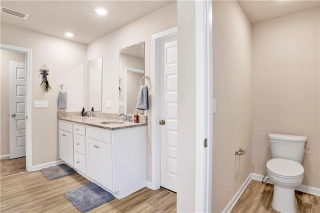 full bath with double vanity, baseboards, visible vents, wood finished floors, and a sink