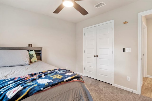 bedroom featuring ceiling fan, light carpet, visible vents, baseboards, and a closet