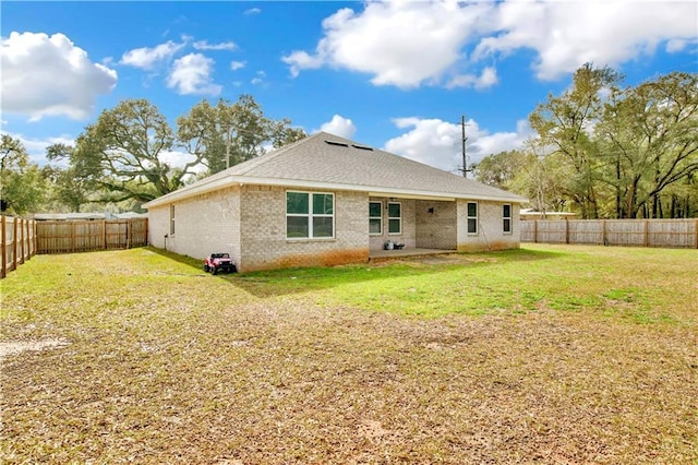 back of property with brick siding, a lawn, and a fenced backyard