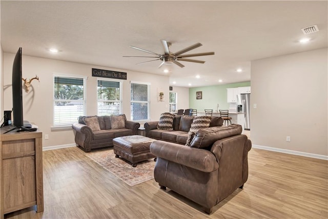 living room with baseboards, light wood-type flooring, visible vents, and recessed lighting