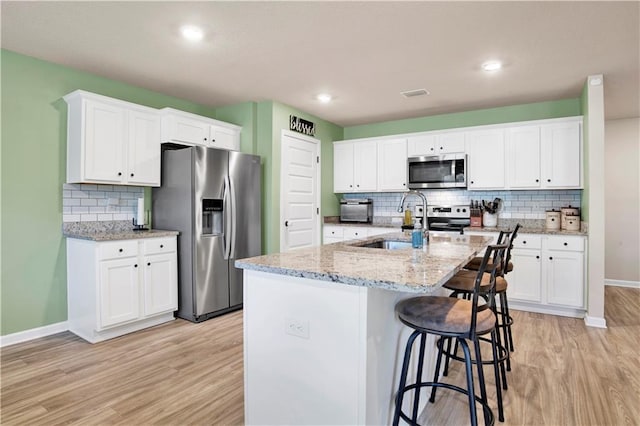 kitchen featuring an island with sink, visible vents, appliances with stainless steel finishes, and white cabinets