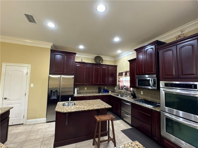 kitchen with a kitchen bar, sink, a center island, light tile patterned flooring, and stainless steel appliances