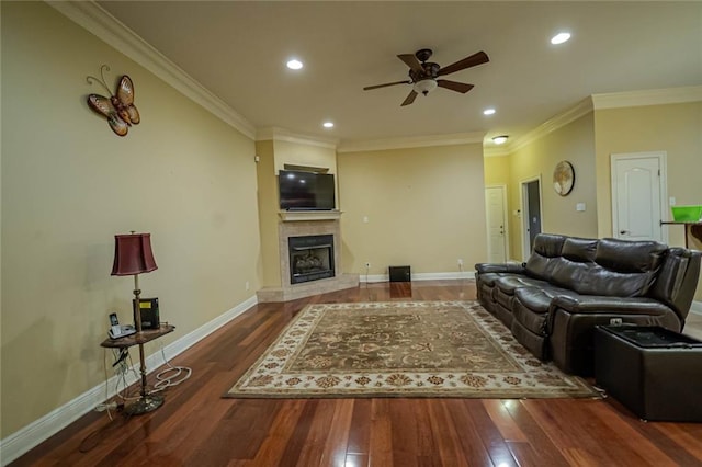 living room featuring ceiling fan, crown molding, dark wood-type flooring, and a tile fireplace