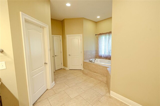 bathroom with tiled bath and tile patterned flooring