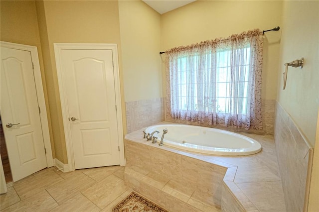 bathroom with tiled tub and tile patterned flooring