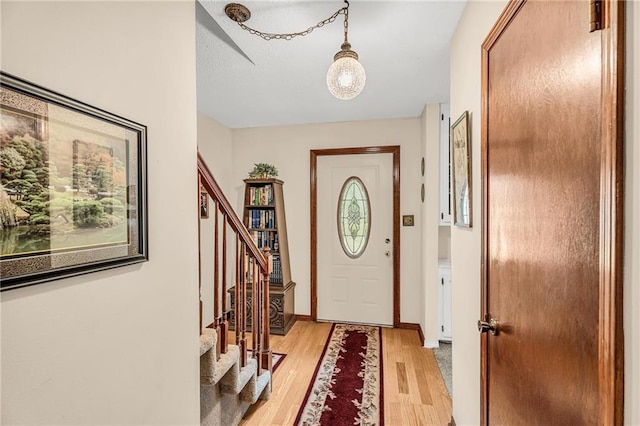 entrance foyer with stairs, baseboards, and light wood-style floors