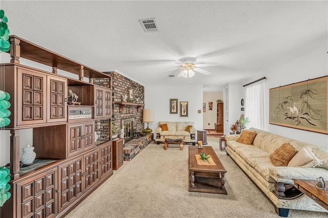 living area featuring a textured ceiling, carpet flooring, visible vents, a ceiling fan, and a brick fireplace